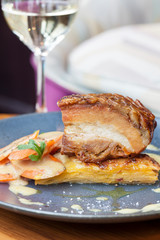 Roasted pork belly meat served with glass of white wine