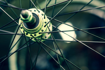 Bicycle repair workshop. On the hook hang new wheels. The hub is black and the spokes and rim are silver. The old bike here is gets a second chance. Parts close-up.