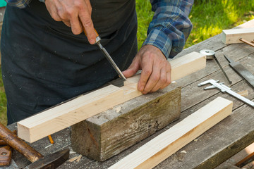 front view of a senior carpenter hands working with a chisel outdoors during sunny day