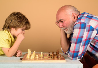 Checkmate. Little boy think or plan chess game. Games and activities for children. Grandfather and grandson playing chess. Child boy playing chess with grandfather. Little boy learning to play chess.