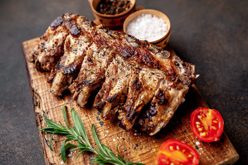 Grilled pork ribs with spices on a cutting board on a stone background 