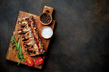 Obraz na płótnie Canvas Grilled pork ribs with spices on a cutting board on a stone background with copy space for your text.