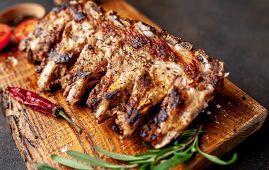 Grilled pork ribs with spices on a cutting board on a stone background 