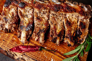 Grilled pork ribs with spices on a cutting board on a stone background 