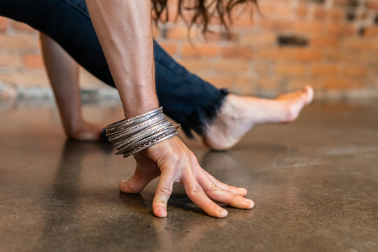 A Close Up View On The Hand Of A Woman Wearing Silver Bracelets During A Vinyasa Yoga Workout, In A Leg Stretch Pose With Hands Resting On Floor