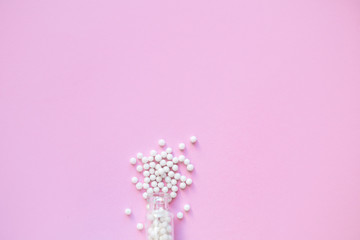 Homeopathy globules in glass bottles on a pink background. Alternative homeopathy herbal medicine, pills. Copyspace for text.