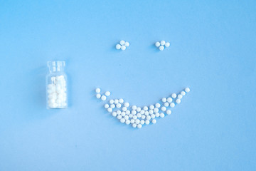 homeopathic globules and glass bottle on blue background. Alternative Homeopathy medicine herbs, healtcare and pills concept. Flatlay. Top view. copyspace for text.