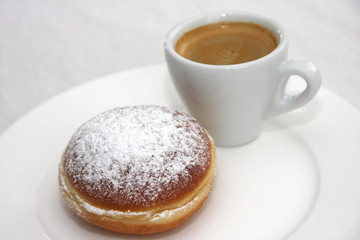 Fresh homemade Austrian Carnival Donut so called Austrian Faschingskrapfen or Berliner, sweet Krapfen filled with apricot jam and icing sugar and espresso on white plate close up on white Background