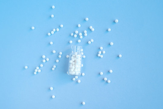 Homeopathy globules in glass bottles on a blue background. Alternative homeopathy herbal medicine, pills. Copyspace for text.