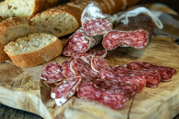 Sausage fuet with white bread on the natural wooden board. Healthy food concept.