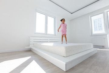 Cute little girl jumping on white bed