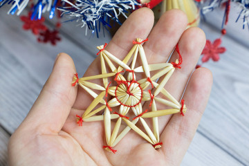 Christmas decoration from straws in the form of a star..A woman holds a handmade Christmas decoration in her hand.