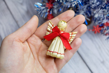 A woman holds a straw Christmas angel in her hand..Handmade Christmas toy.