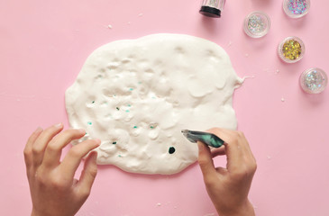 Child hands with home-made slime.  Baby makes a home made slime with glue and glitters on background.