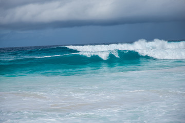 Naklejka na ściany i meble Turquoise ocean waves with dramatic sky