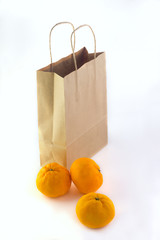  tangerines lying near a paper craft package on a white background