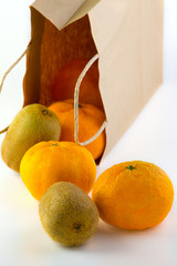  kiwi and mandarin spilled out of a paper bag on a white background