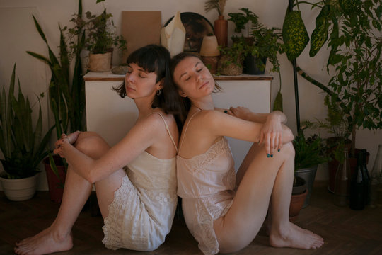 two girls are sitting on the background of the nightstand with paintings and flowers