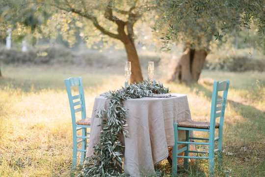 Table for two setup in a olive plantation decorated with olive tree branches