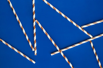 Background made of coctail straws with golden stripes on blue color.