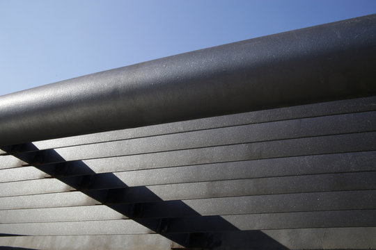 Metal girder lath structure. Detail of industrial building. Abstract modern architecture. Geometric background with parallel lines and angular shadow on linear pattern.