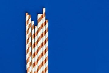Background made of coctail straws with golden stripes on blue color.