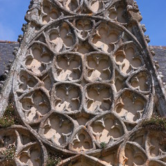 Blind gothic circular rose tracery at the city church facade of Pont-Croix in Bretagne, France