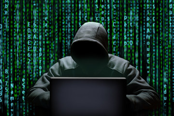 A hacker uses a laptop to crack internet passwords. Cyber spy on the background of binary code