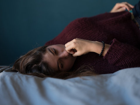 Worried young woman lying on bed