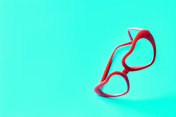 Red glasses in lenses in the shape of hearts on a blue turquoise background. The concept of good vision, love and Valentine's Day. Vertical composition. Love at first sight. Space for design text