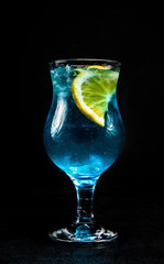Blue lagoon cocktail with a slice of lemon. a glass with an alcoholic drink on a black, isolated background.