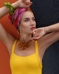 Bright summer portrait of young attractive woman in yellow swimsuit in african colorful style