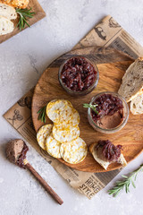 Fototapeta premium Fresh homemade chicken liver pate and onion chutney (marmalade) in a jar, bread and crackers on a wooden plate. Light grey background, selective focus.