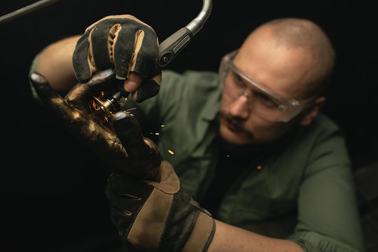 Artisan shaping metal bust with grinder