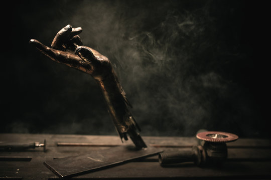sculpture of a metal hand with smoke on the background
