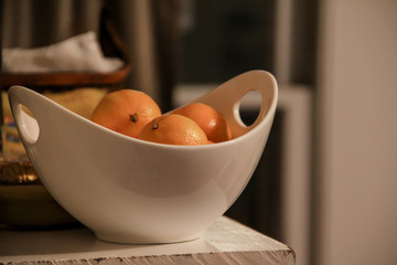 White bowl full of clementines set up on a shelf