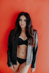 brunette girl in leather jacket and black lingerie on a red background