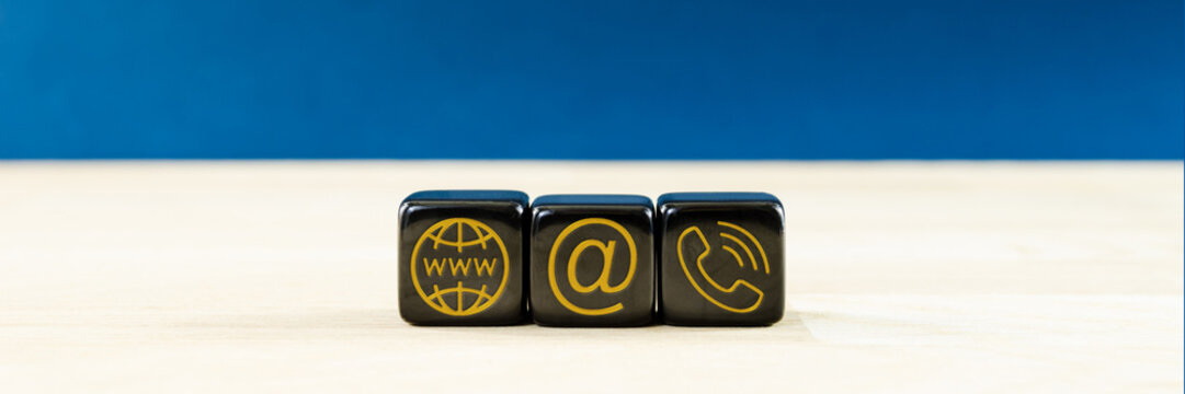 Wide view of customer service image with black dices with gold contact information and location icons on them. Over blue background.