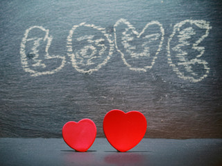 Two red hearts side by side and chalk sign love in the background. Saint Valentine abstract background.