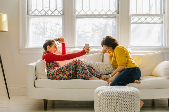 Mother And Daughter Laughing and Looking at Mobile Phone