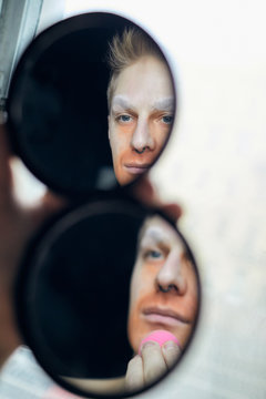 Man Using Orange Corrector In Mirror Reflection