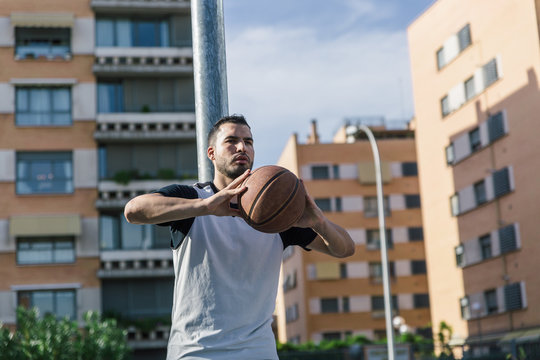 Strong athlete basketball player is leaning on a metal column with his ball