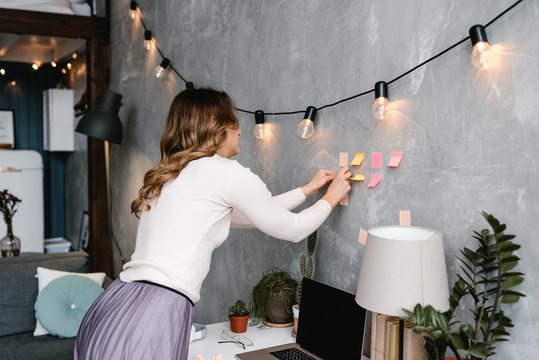 Woman attaching sticky notes to wall
