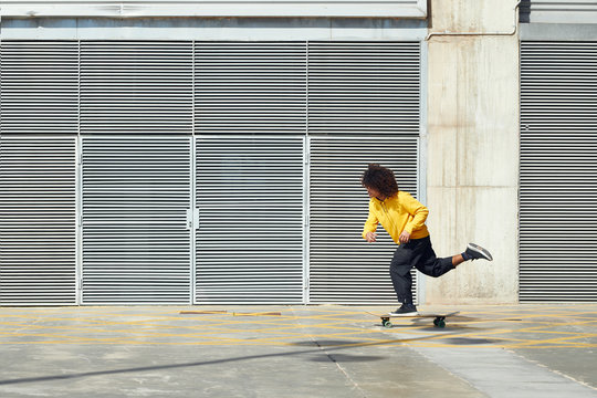 Ethnic man skating on sunny street