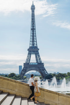 Anonymous couple walking on steps and admiring Eiffel Tower