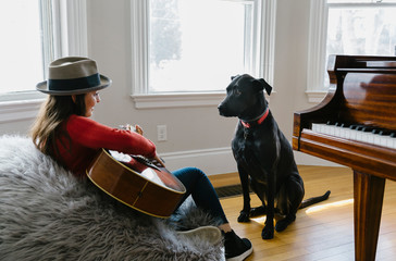 Teenager Playing Guitar with her Dog