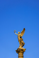 Fototapeta premium Gold lady monument on a blue sky background, Prague, vertical