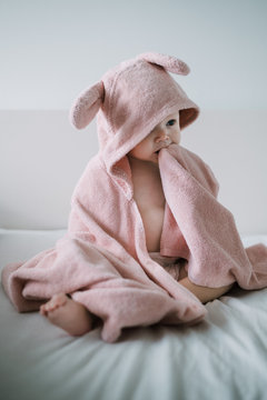 A baby girl sitting in her pink towel after a lovely bath