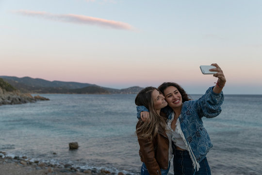 Two female friends taking a selfie together by the sea