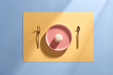 French colorful macarons in pink ceramic dish on blue and yellow pastel background